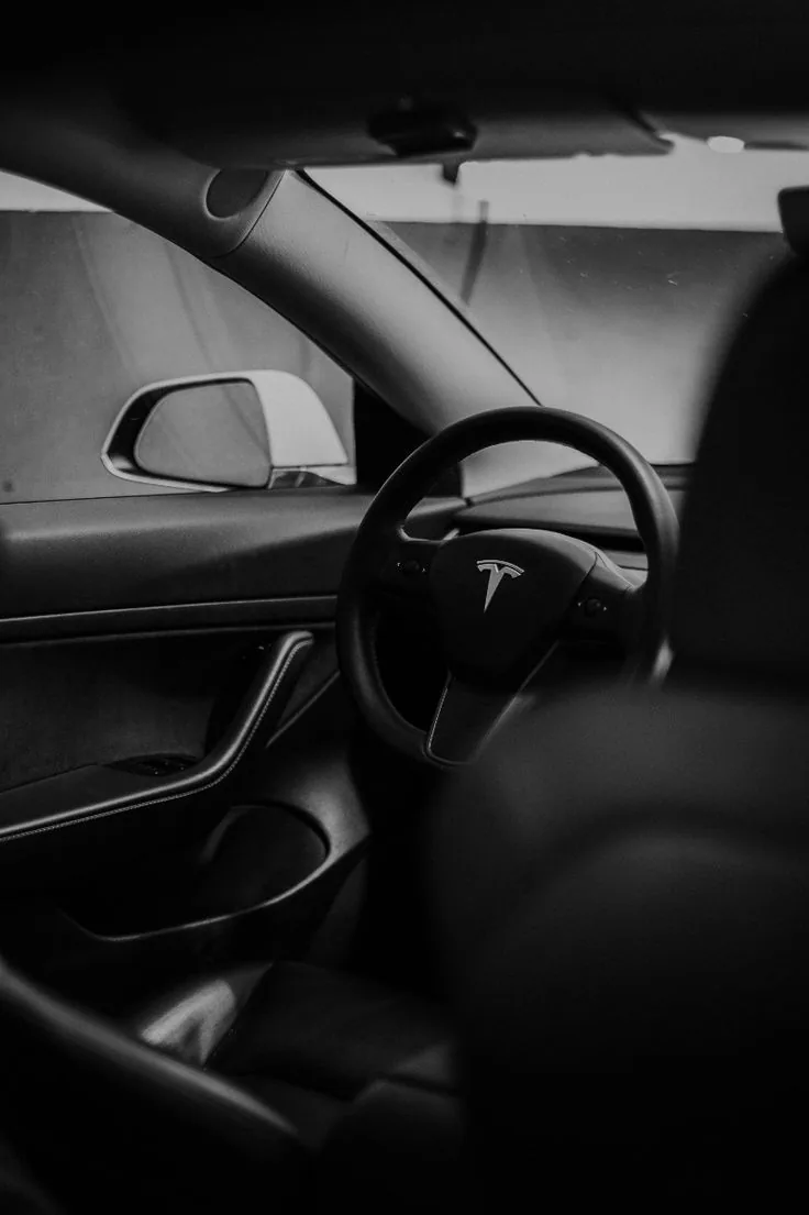 Schwarz-Weiß-Fotografie eines Tesla-Innenraums mit Blick auf das Lenkrad.
