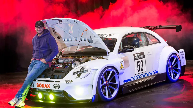 Ein Mann neben einem weißen Tuning-Auto mit geöffneter Motorhaube vor rotem Rauch.