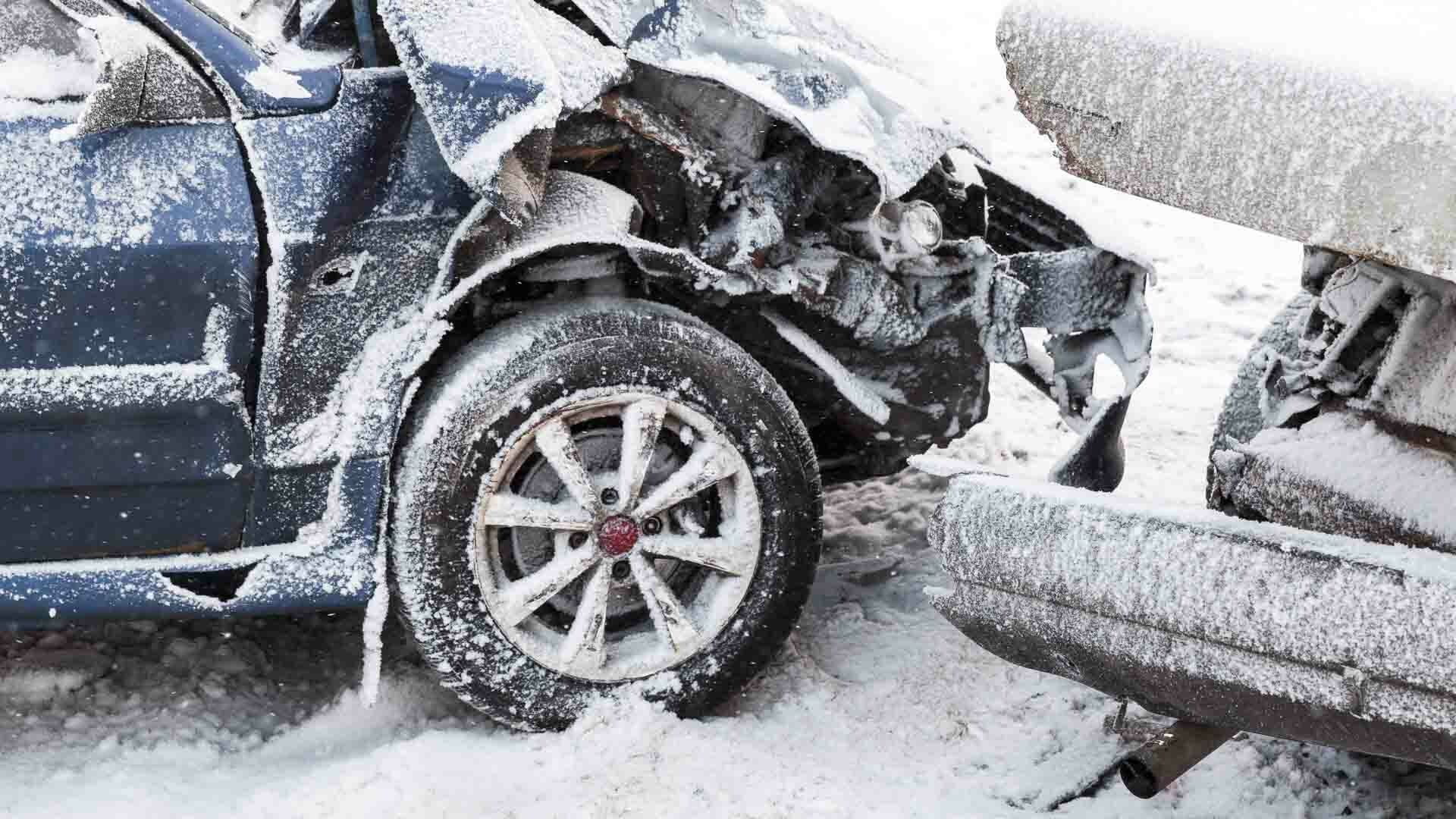 Zwei beschädigte Autos mit Schnee an Karosserie und Reifen.