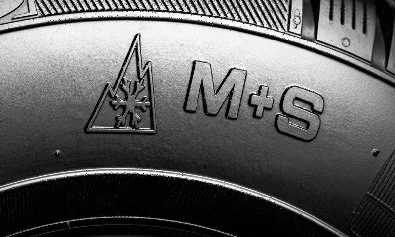 Nahaufnahme einer Reifenflanke mit dem Alpine-Symbol aus Berg und Schneeflocke sowie der Kennzeichnung M+S.