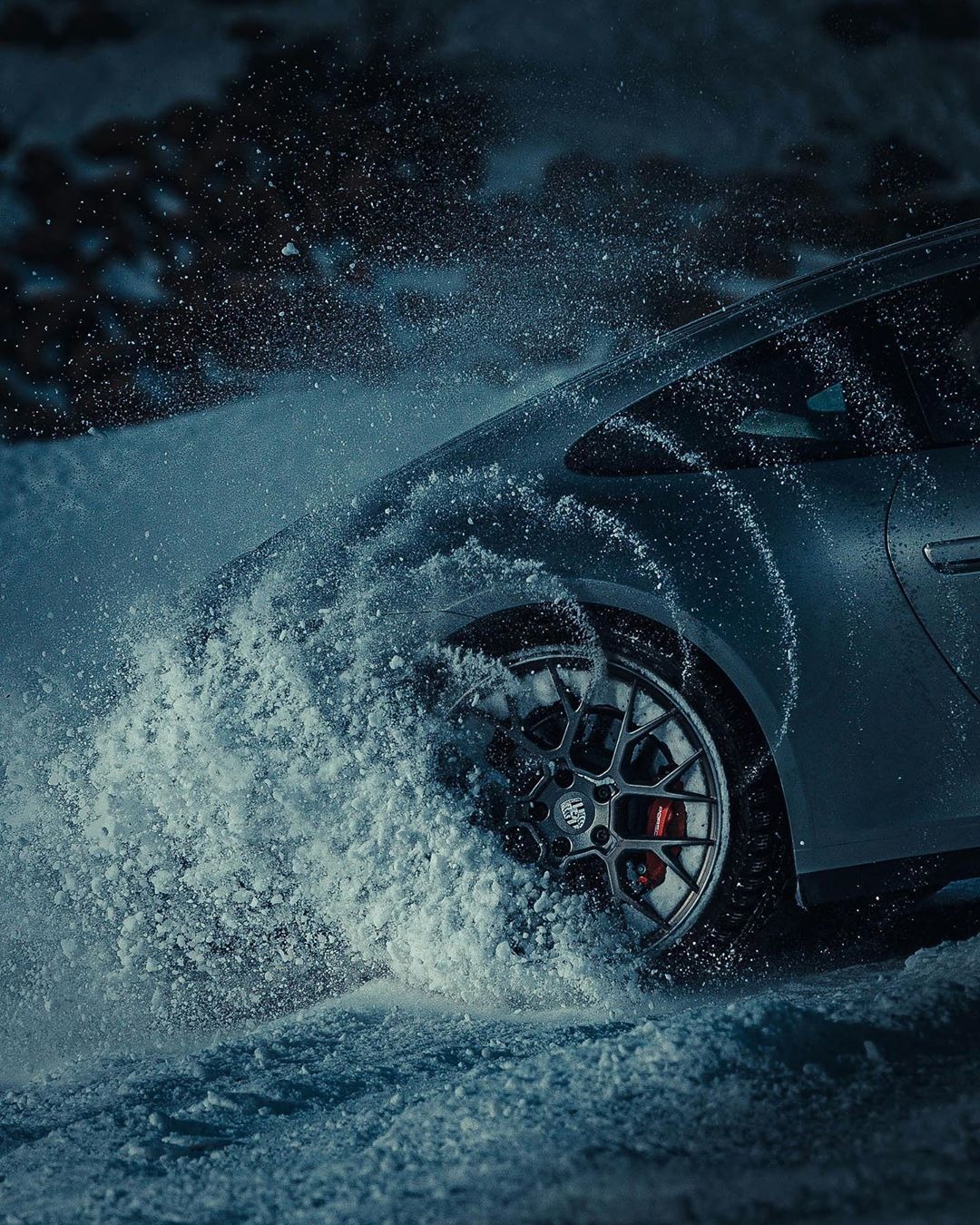 Autoreifen und Radkasten mit aufgewirbeltem Schnee.