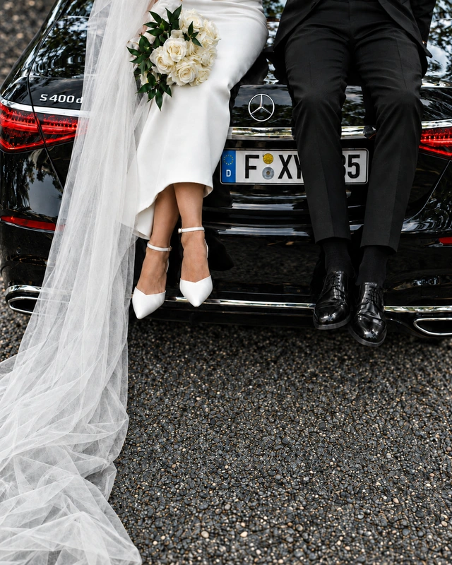 Brautpaar mit weißen Rosen am schwarzen Mercedes der S-Klasse
